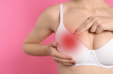 Image of Woman checking her breast on pink background, closeup