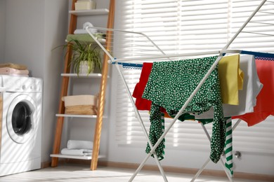 Photo of Different apparel drying on clothes airer in bathroom, space for text