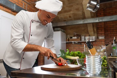 Photo of Professional chef cutting fresh tomato in restaurant kitchen