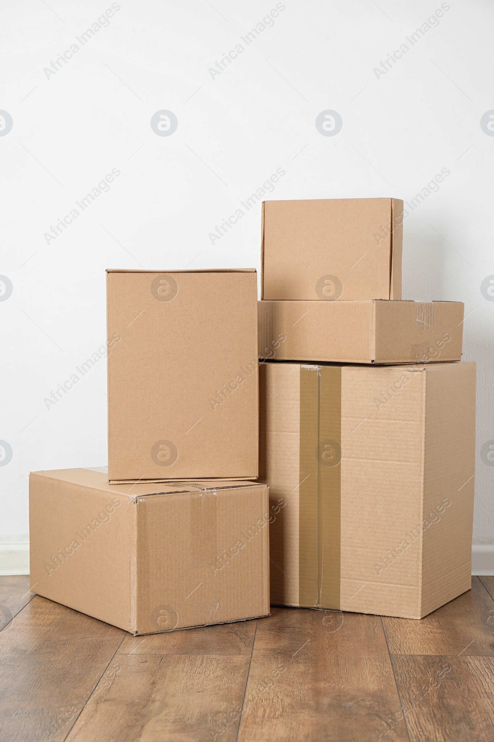 Photo of Pile of cardboard boxes near white wall indoors