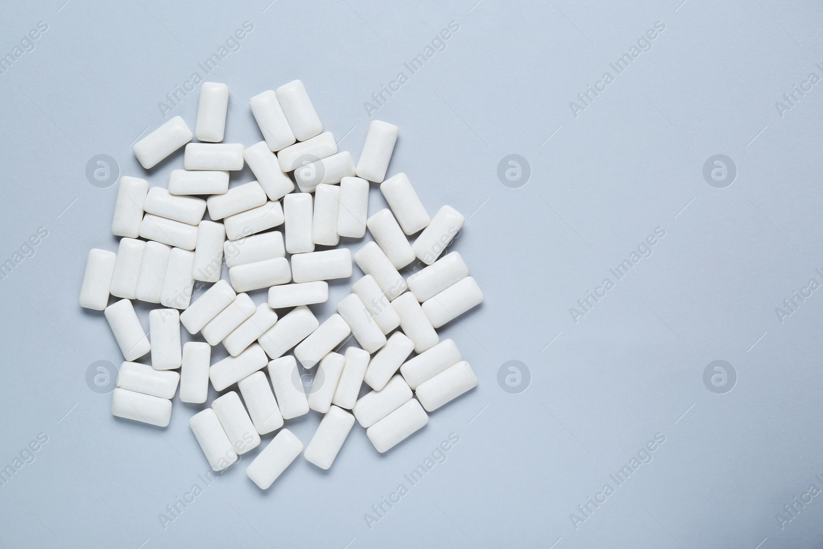 Photo of Tasty white chewing gums on light grey background, flat lay. Space for text