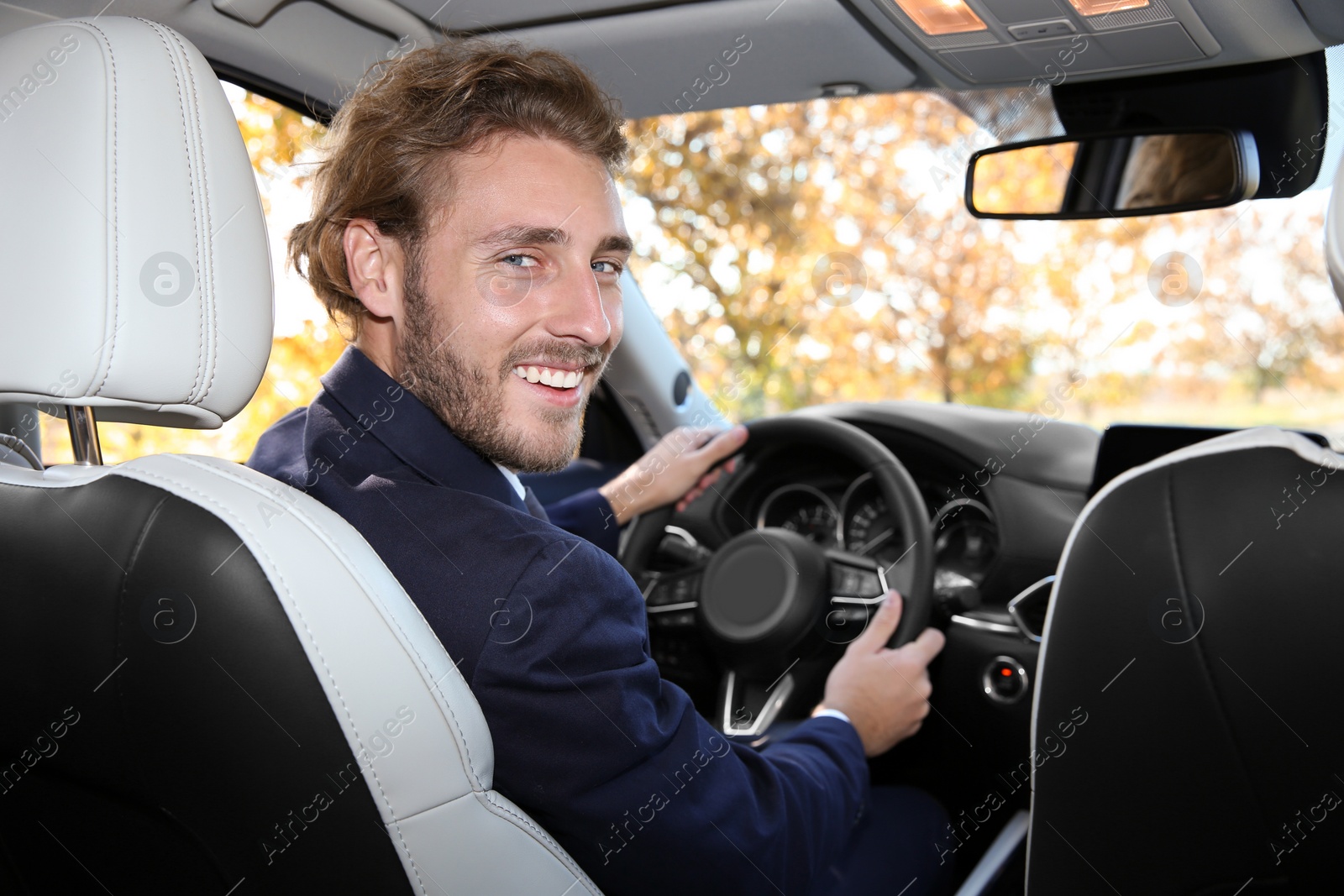 Photo of Young handsome man in driver's seat of modern car