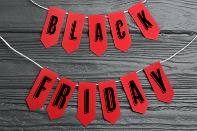 Photo of Words BLACK FRIDAY made with red tags on dark wooden background, flat lay