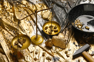 Photo of Gold nuggets, vintage scales, hammer and wok on plastic stretch wrap