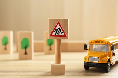 Photo of Traffic sign Attention children crossing street and toy bus on wooden table. Passing driving license exam