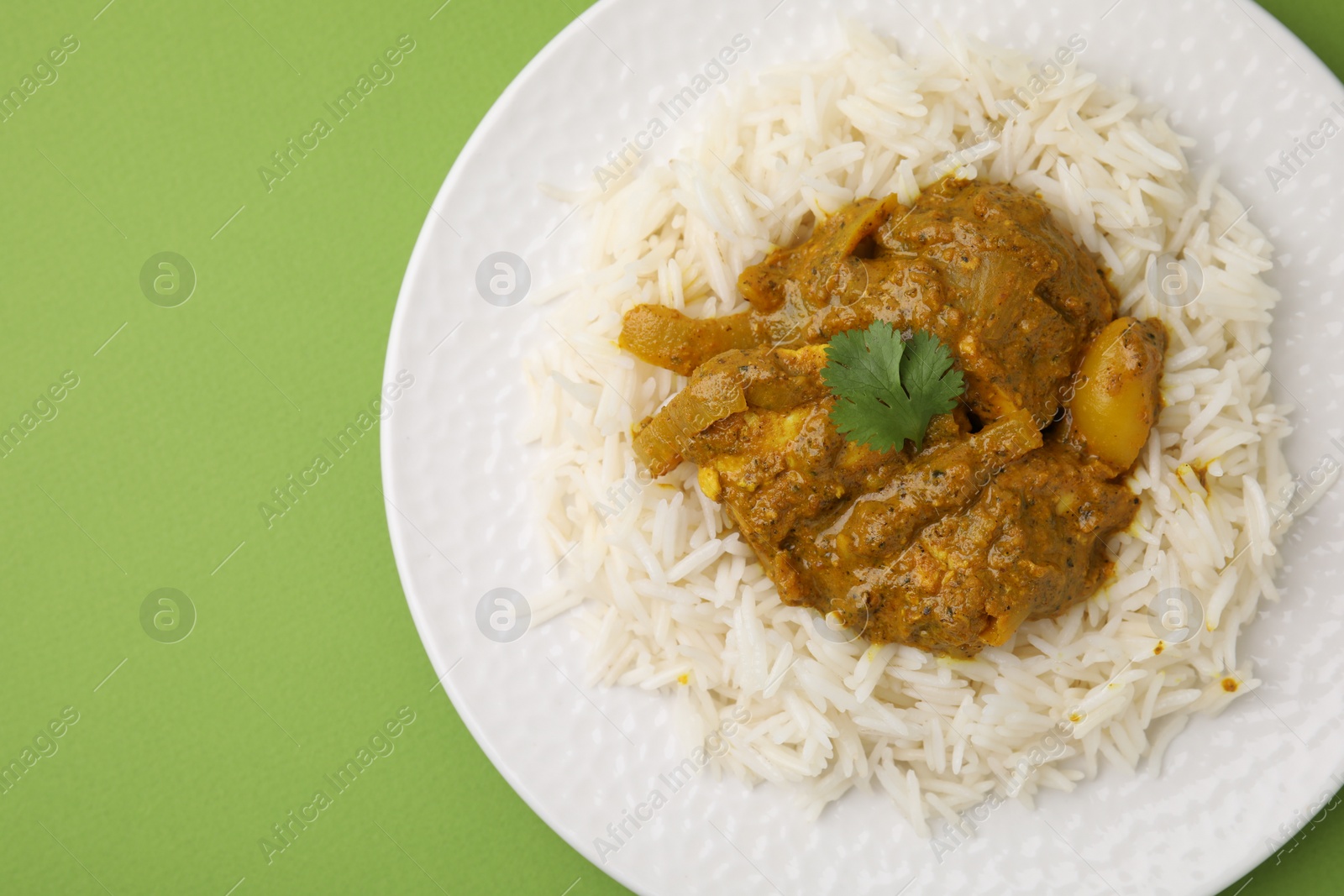 Photo of Delicious chicken curry with rice on green background, top view