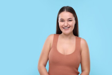 Photo of Smiling woman with dental braces on light blue background. Space for text