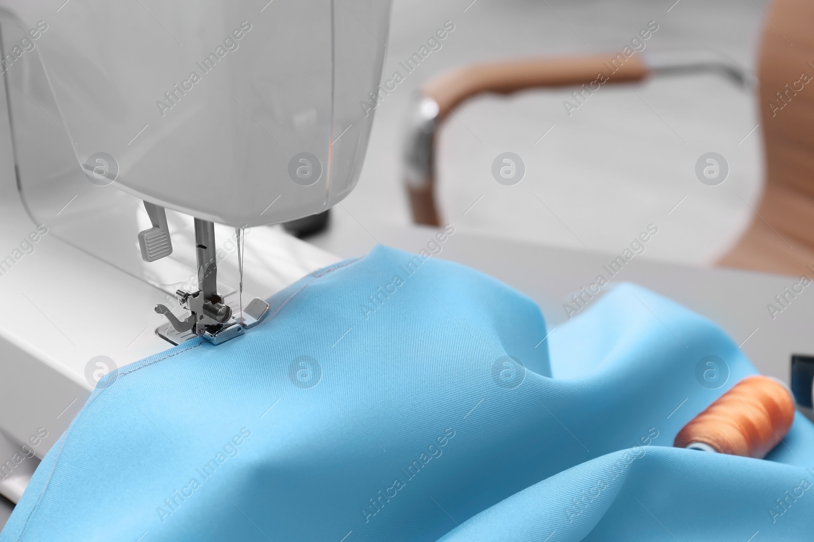 Photo of Sewing machine with fabric on table in tailor workshop, closeup