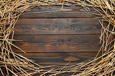 Photo of Frame made of dried hay on wooden background, top view. Space for text