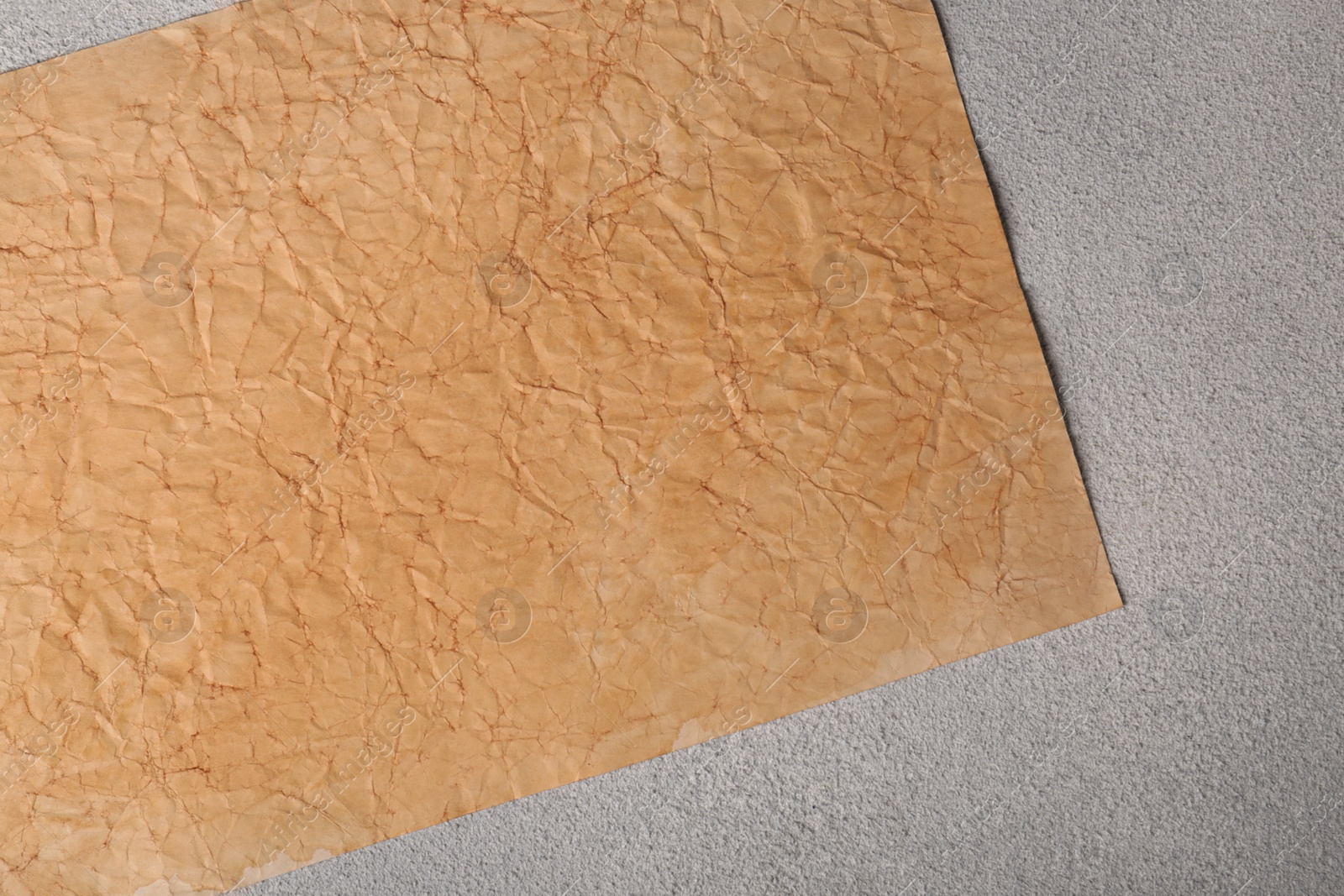 Photo of Sheet of old parchment paper on light gray textured table, top view