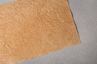 Photo of Sheet of old parchment paper on light gray textured table, top view