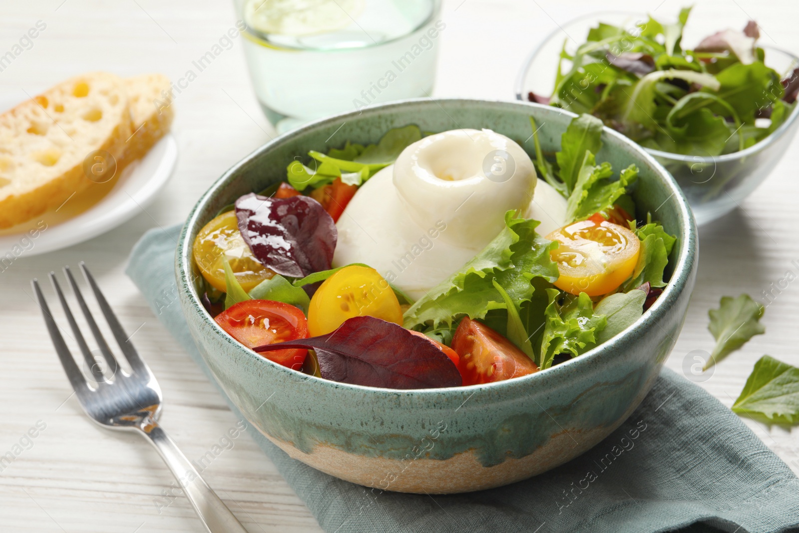 Photo of Delicious burrata salad with colorful cherry tomatoes and arugula served on white wooden table