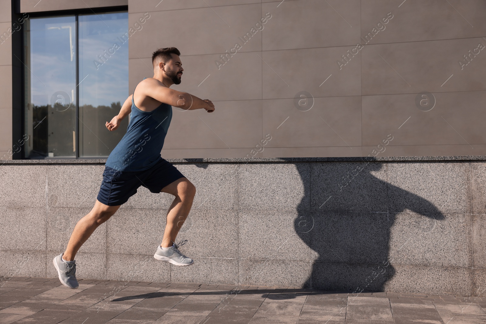 Photo of Young man running near building outdoors. Space for text