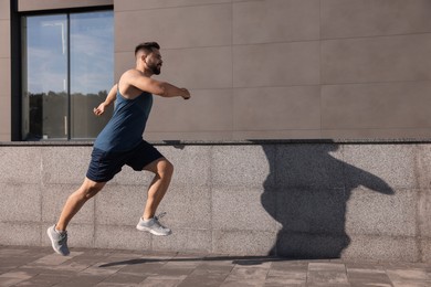 Photo of Young man running near building outdoors. Space for text