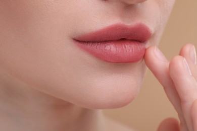 Photo of Young woman with beautiful full lips on beige background, closeup