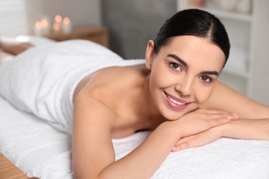Photo of Beautiful happy woman relaxing on massage table in spa salon