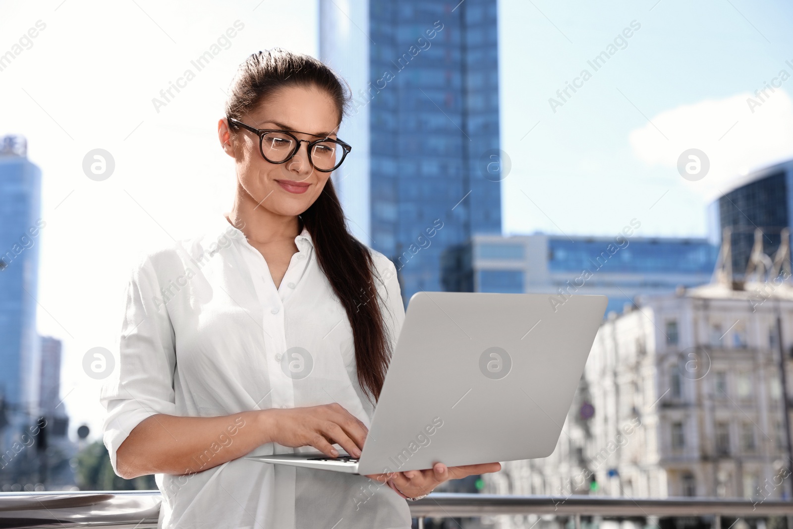 Photo of Beautiful businesswoman with laptop on city street