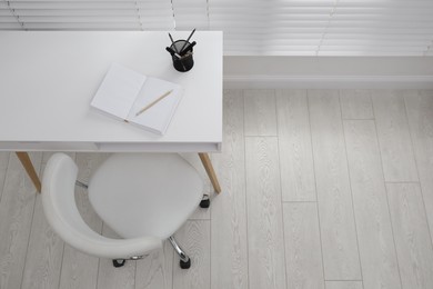 Photo of Stylish workplace with white desk and comfortable chair near window indoors, above view. Interior design