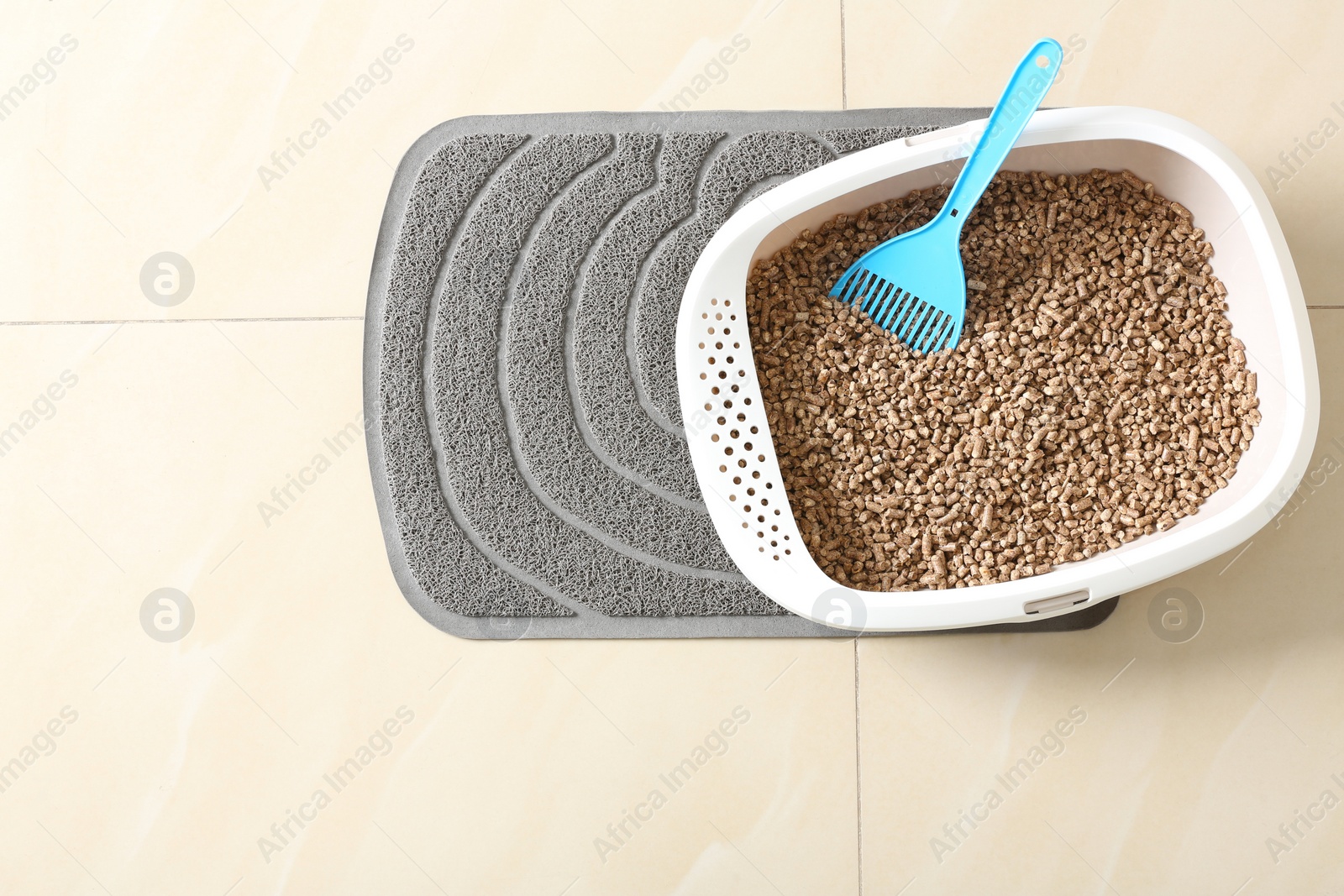 Photo of Cat tray with biodegradable litter and scoop on floor, top view. Space for text