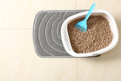 Photo of Cat tray with biodegradable litter and scoop on floor, top view. Space for text
