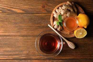 Cup of delicious ginger tea, honey and lemons on wooden table, flat lay. Space for text