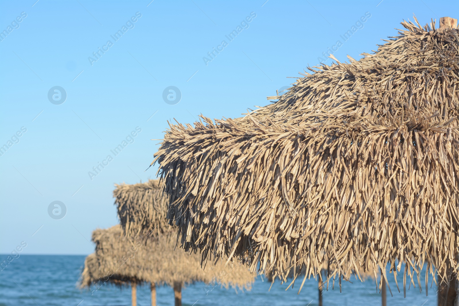 Photo of Beautiful straw beach umbrellas against blue sky