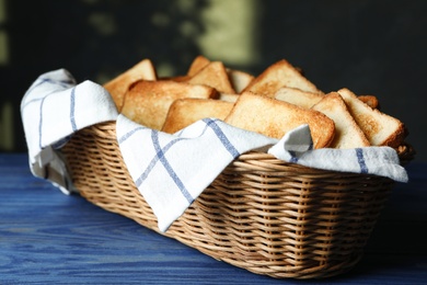 Photo of Slices of toasted bread in basket on blue wooden table