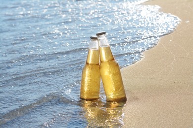 Photo of Bottles of cold beer on sandy beach near sea