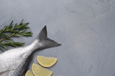 Photo of Fresh raw dorado fish, lemon and rosemary on grey table, flat lay. Space for text