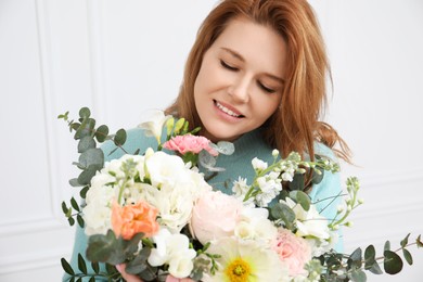 Photo of Beautiful woman with bouquet of flowers near white wall indoors