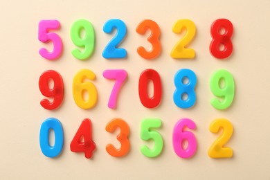 Colorful numbers on beige background, flat lay