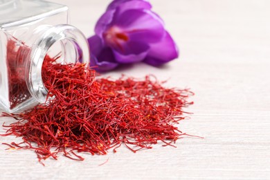 Photo of Dried saffron and crocus flower on white wooden table, closeup. Space for text