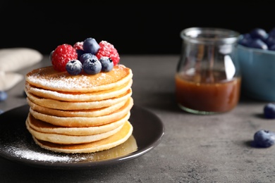 Photo of Tasty pancakes with berries and sugar powder on plate
