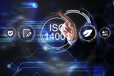 Image of Man pointing at virtual screen with text ISO 14001 and different icons, closeup