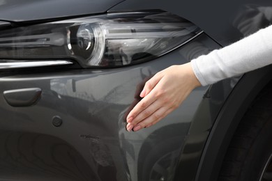 Woman near car with scratch outdoors, closeup view