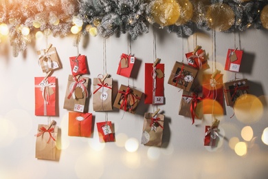 Image of Christmas Advent calendar with gifts and decor hanging on light wall. Bokeh effect