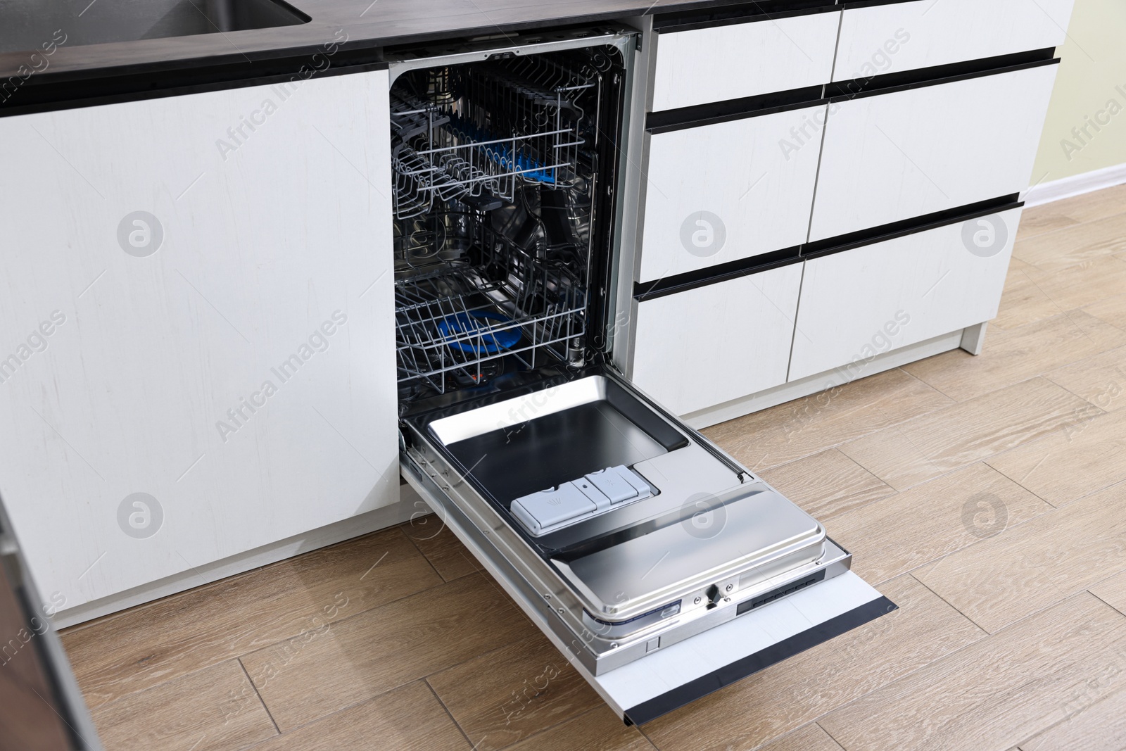 Photo of Open clean empty dishwasher in kitchen. Home appliance