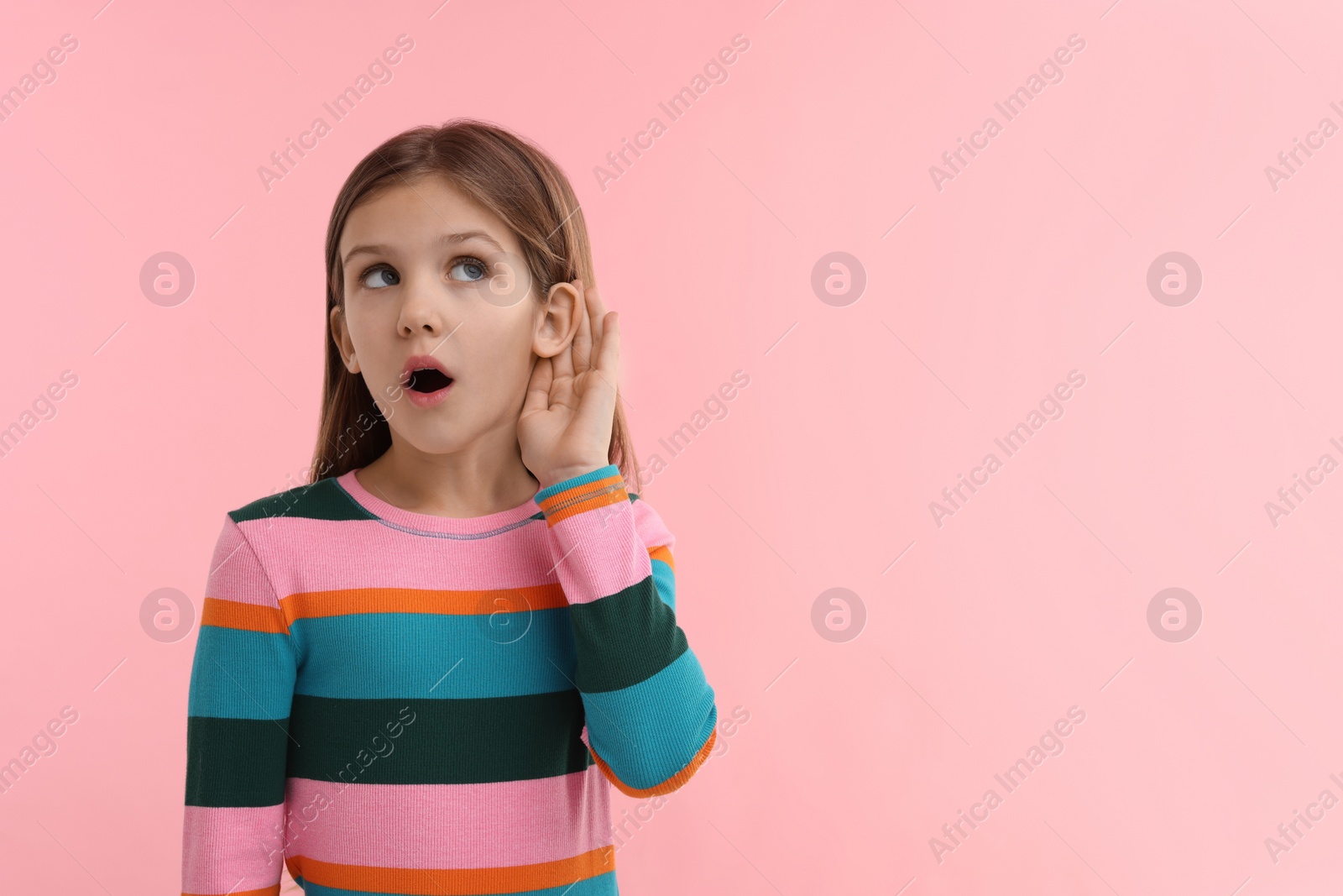 Photo of Little girl with hearing problem on pink background, space for text