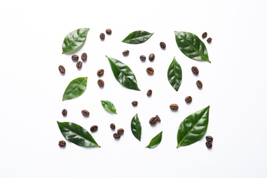 Fresh green coffee leaves and beans on white background, top view