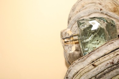 Photo of Luxury perfume in bottle on textured surface against beige background, space for text