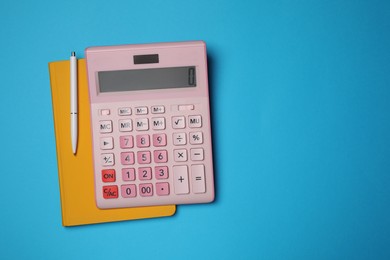 Calculator, notebook and pen on light blue background, flat lay with space for text