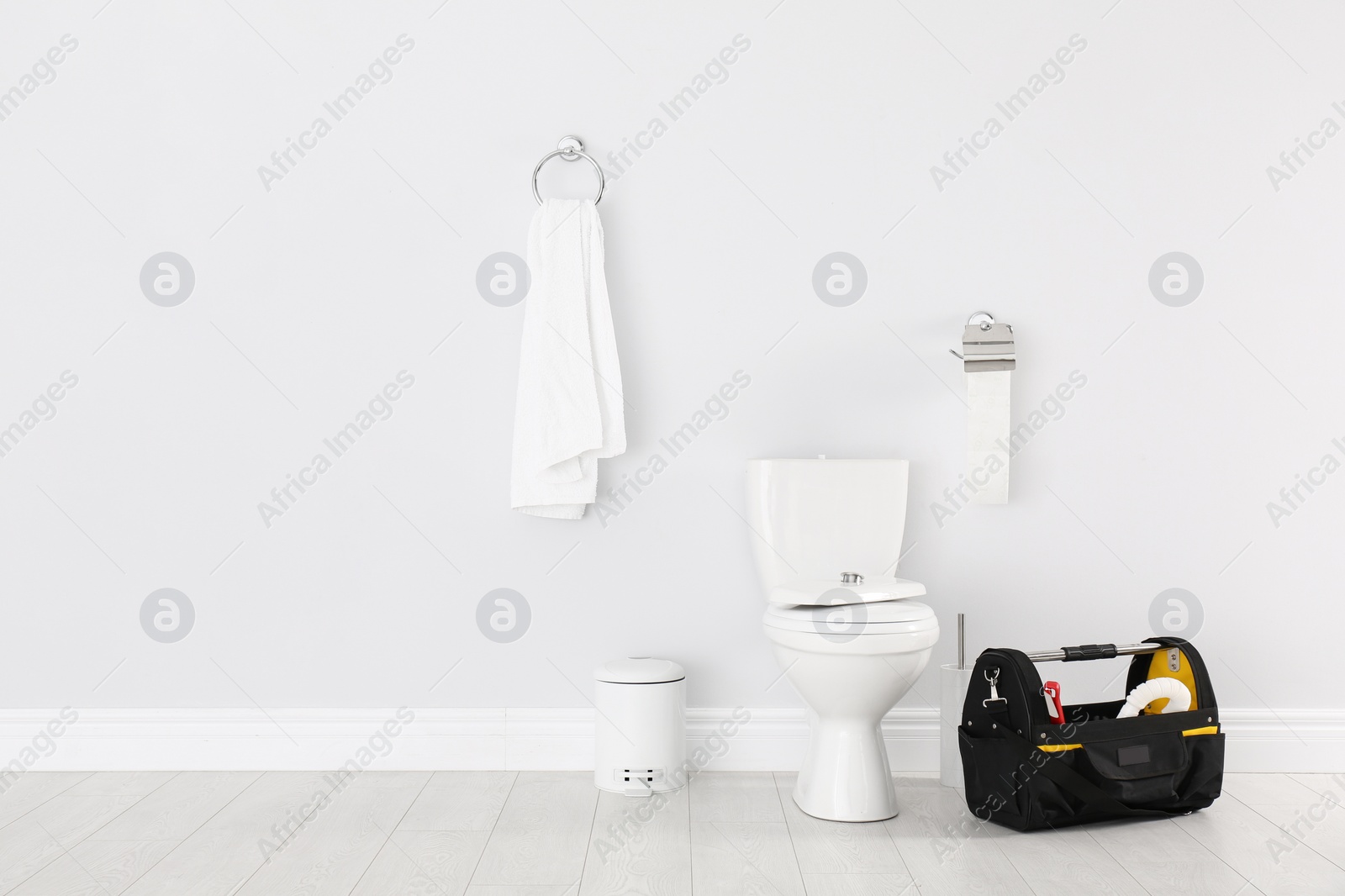 Photo of Plumbing tool kit bag near toilet bowl in bathroom