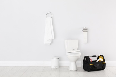 Photo of Plumbing tool kit bag near toilet bowl in bathroom