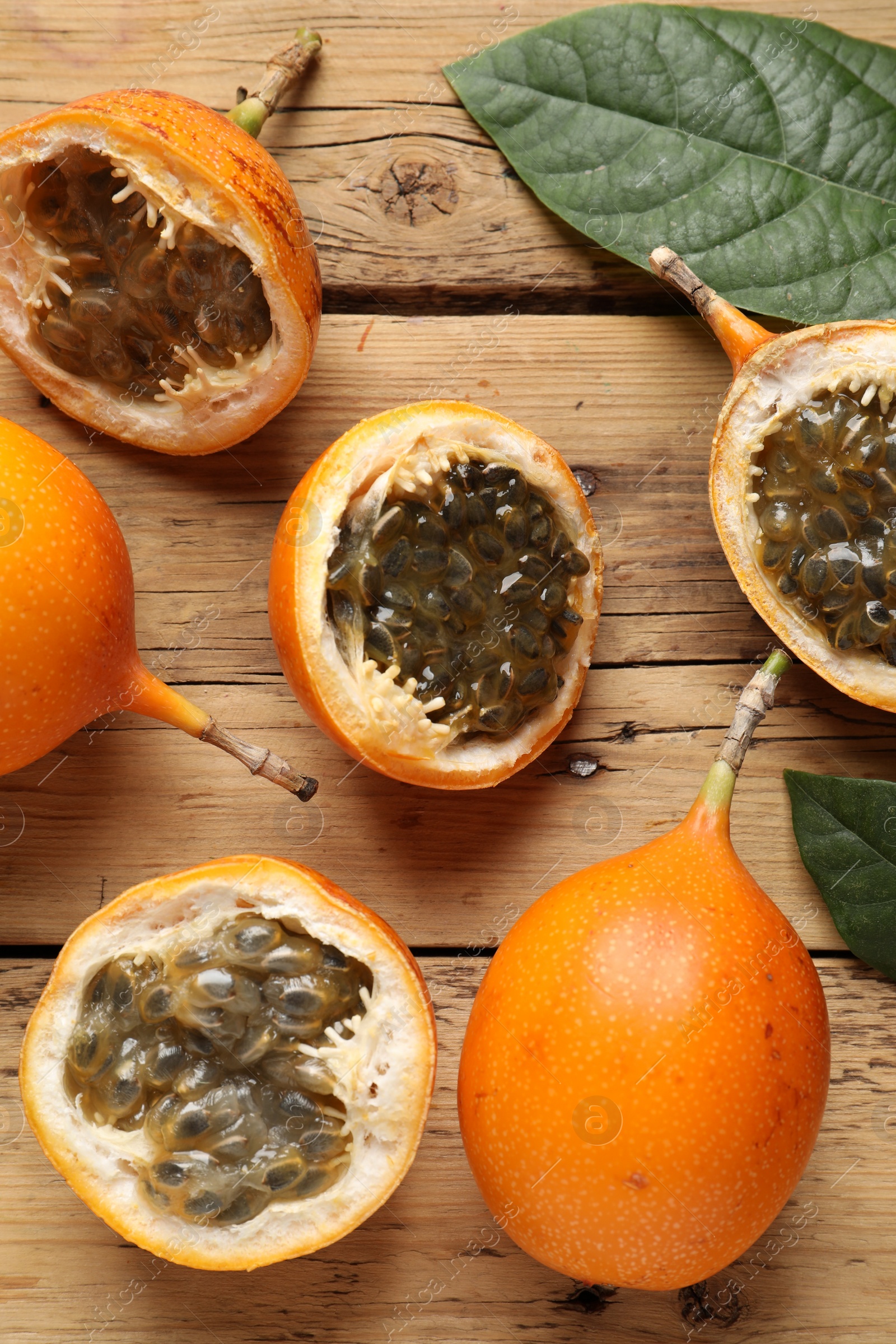 Photo of Delicious ripe granadillas on wooden table, flat lay