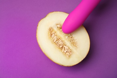 Photo of Half of melon and vibrator on purple background, flat lay. Sex concept