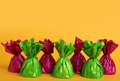 Photo of Candies in colorful wrappers on yellow background