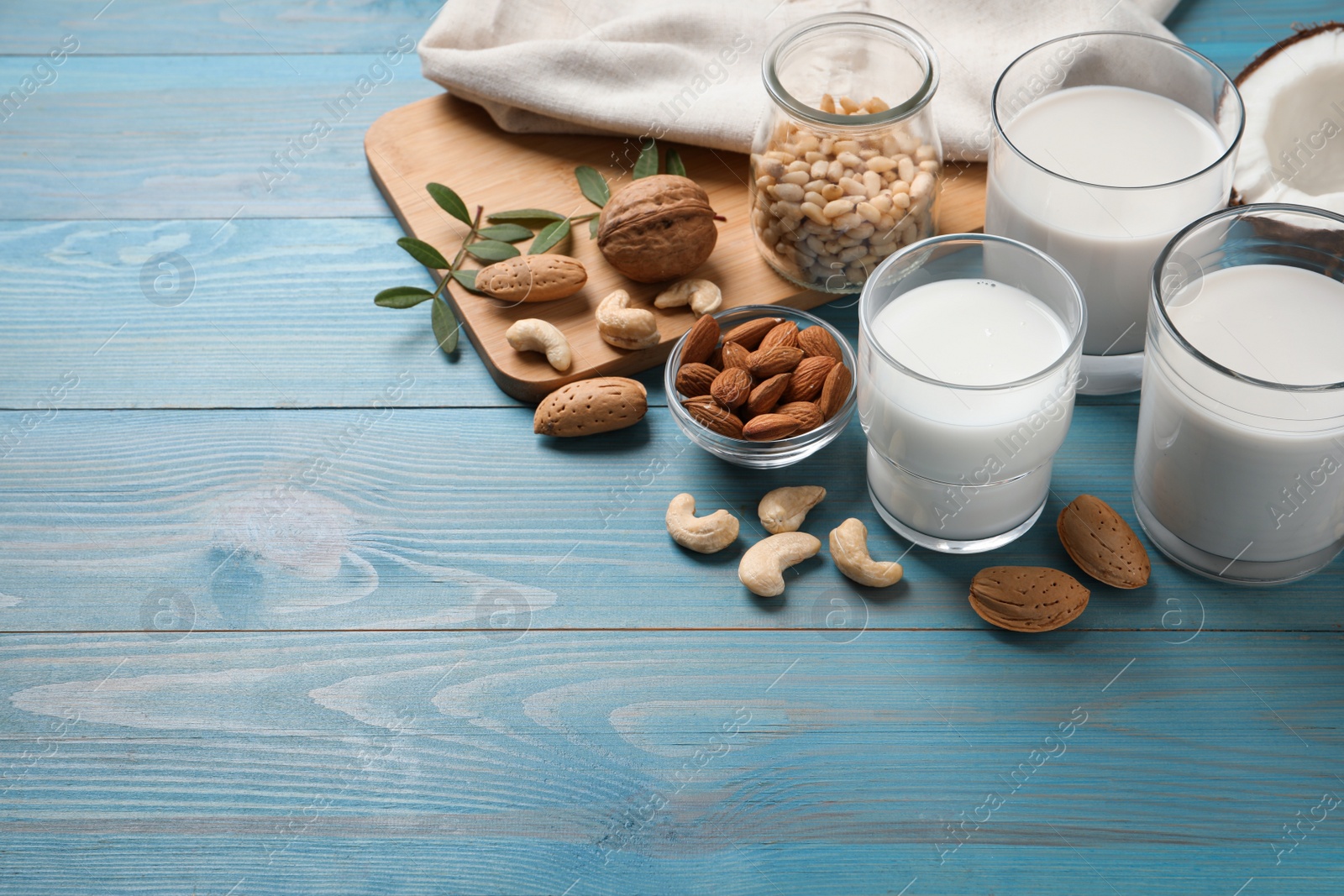 Photo of Different nut milks on light blue wooden table. Space for text