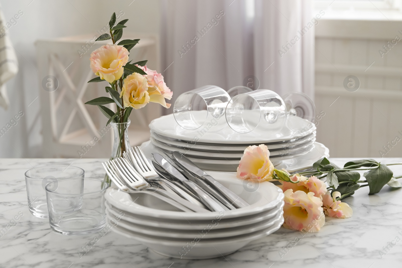 Photo of Set with clean dishes and flowers on white marble  table