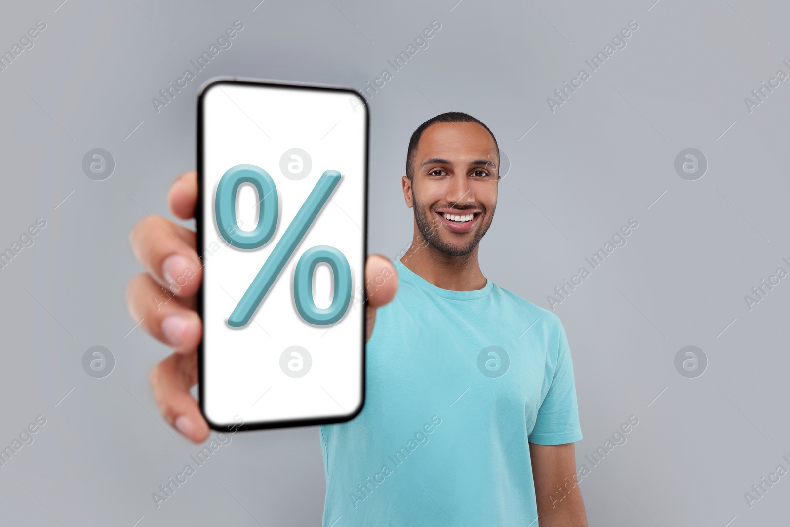 Image of Discount, offer, sale. Man showing mobile phone with percent sign on screen, grey background