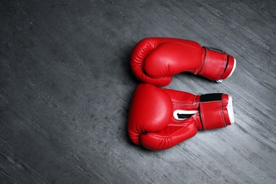Photo of Pair of red boxing gloves on grey stone background, flat lay. Space for text